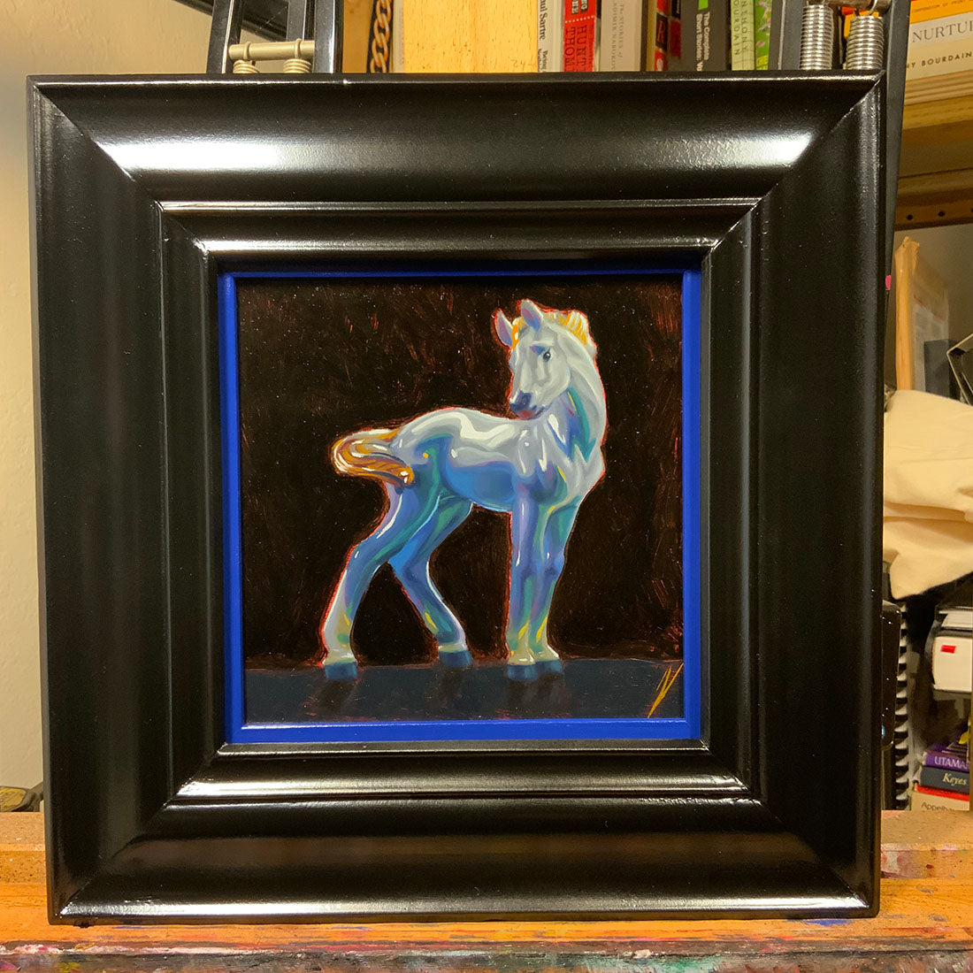 Framed artwork of a colorful horse on a dark background