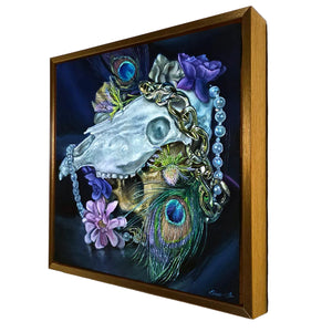 Framed artwork with a skull, peacock feather, and flowers on a dark background
