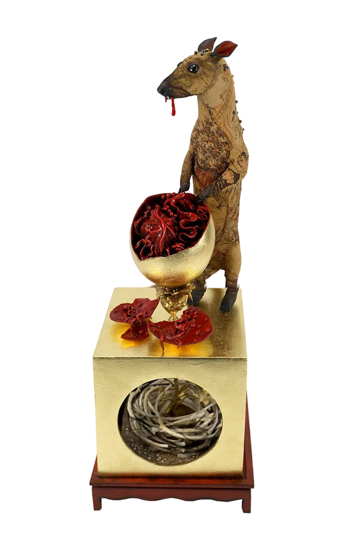 A surreal figurative art sculpture featuring a standing deer holding a goblet of red liquid, positioned on top of a gold pedestal with a circular cutout showing gray twigs, set against a plain white background.