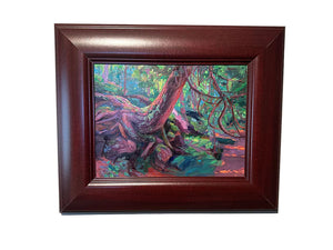 Framed painting of a forest scene with colorful trees on a beige wall.