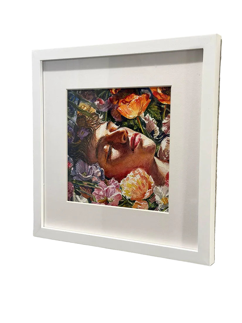 Framed artwork of a person's face surrounded by flowers on a textured wall.