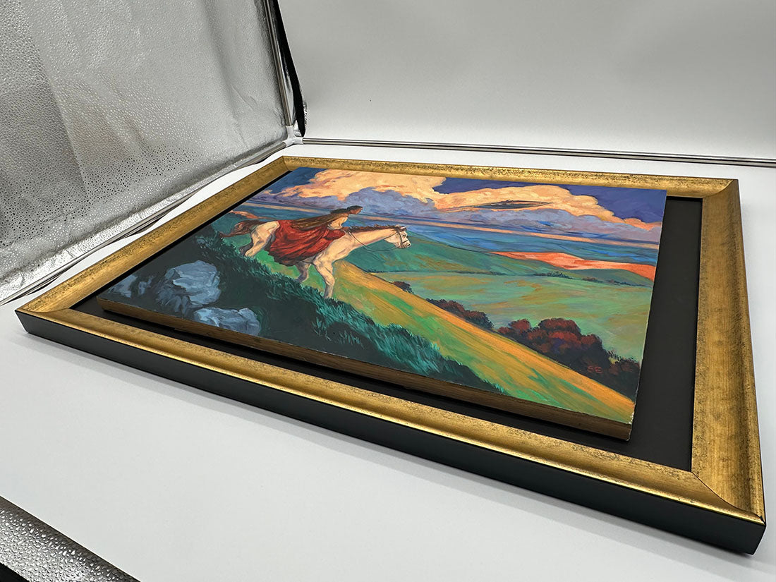 Framed painting of a woman running on grass with a colorful sky.