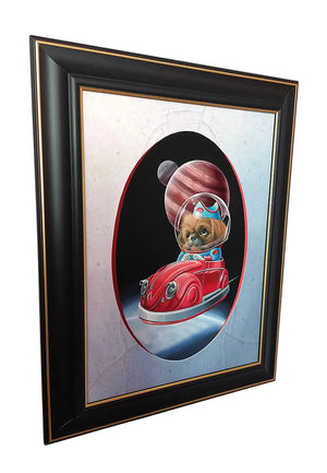 Framed wall art featuring a cartoon dog in a red spacecraft wearing a striped space helmet, set against a black oval background with a silver textured outer field. The piece is housed in a black frame with gold trim, hanging on a light-colored wall.