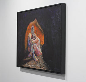 A framed square canvas painting hanging on a white wall, depicting a seated figure in a dark cave-like scene with a glowing orange and pink opening behind them.