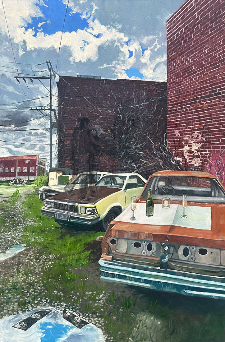 Two vintage cars modified as outdoor dining tables with drinks on a grassy area near a brick building.