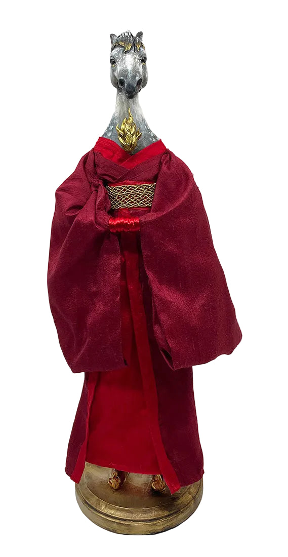 Decorative figure of a horse draped in red fabric with gold accents on a white background