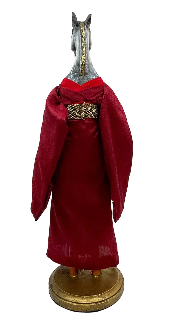 Horse figurine wearing a red garment on a white background